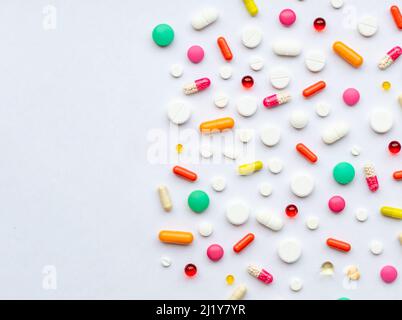 Mise en page créative de pilules et capsules colorées sur fond vert. Concept médical minimal. Banque D'Images