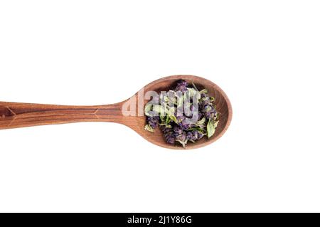 Plante séchée Prunella vulgaris connue sous le nom de commune auto-guérir, guérir-tout, woundwort. Fleurs violettes sur une cuillère à bois isolée sur fond blanc. Poudre de thé. Banque D'Images