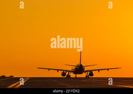 Silhouette d'avion atterrissage au coucher du soleil avec un magnifique ciel rouge en arrière-plan. Avion commercial. Jet privé. Évacuation. Banque D'Images