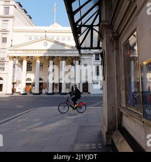 Londres, Grand Londres, Angleterre, mars 08 2022 : le cycliste passe devant le Theatre Royal à Haymarket. Banque D'Images