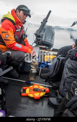 Les clients du bateau de croisière antarctique participent au projet citoyen scientifique, recueillant des échantillons de plancton, température et clarté de l'eau, Danco Island. Banque D'Images