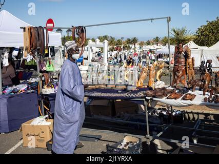 Vendeur africain en robe traditionnelle vendant des masques en bois sculpté à son stand dans le marché du dimanche de Teguise à Lanzarote, Espagne, le 13 mars 2022 Banque D'Images