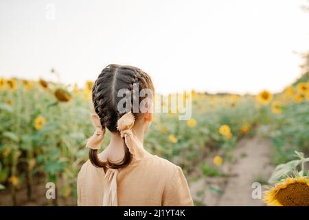 Ambiance ensoleillée en été. Enfant parmi les tournesols Banque D'Images