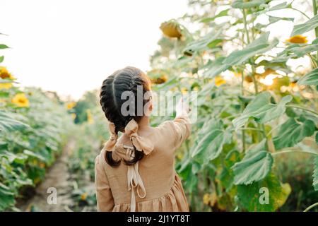 Ambiance ensoleillée en été. Enfant parmi les tournesols Banque D'Images