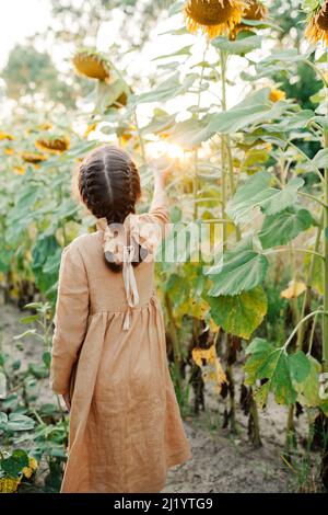 Ambiance ensoleillée en été. Enfant parmi les tournesols Banque D'Images