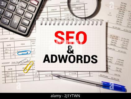 Texte écrit par mot Seo et Adwords. Business concept pour le paiement par clic Digital marketing Google Adsense locked agenda feuilles clips marqueur souris alarme cl Banque D'Images