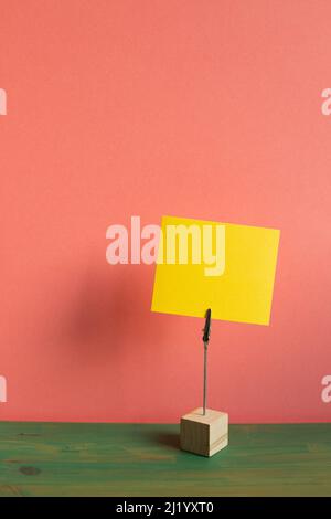 Porte-mémo avec carte vierge sur bureau en bois vert. Fond de mur rose. Espace de copie Banque D'Images