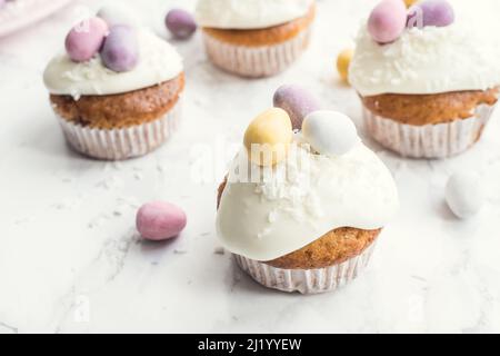 Cupcakes de Pâques glacés décorés de mini œufs au chocolat sur fond de marbre blanc. Joyeuses Vacances De Pâques. Banque D'Images