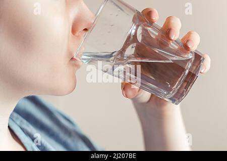 Une femme boit de l'eau propre. Journée mondiale de l'eau. Concept de soins de santé. Régime et détox, augmenter le métabolisme. La main tient un verre d'eau potable. Banque D'Images