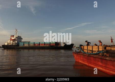 Les ouvriers travaillent sur une barge chargée de sable, alors qu'un cargo traverse la rivière Musi à Palembang, dans le sud de Sumatra, en Indonésie. Du XIe siècle (la chute de Srivijaya) jusqu'au XIIIe siècle, le nom de Srivijaya était parfois encore utilisé même si son territoire est devenu très limité à ce qui est connu sous le nom de Palembang actuel. Cette ancienne capitale de la grande thalassocratie a commencé à être connue sous son nom actuel au XIVe siècle. 'Dans ou vers 1377, Srivijaya a été conquise par les Javanais, et le nom disparaît des œuvres chinoises.' Banque D'Images