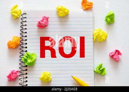 Main pointant vers le concept ROI sur fond de mur brun clair Banque D'Images