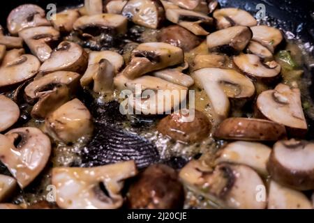 Macro, foyer sélectif sur la cuisson des champignons Bella de bébé dans une grande poêle antiadhésive Banque D'Images