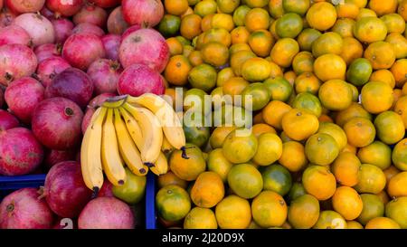 Grenades, citrons, bananes, pommes, mandarines et poires sur une table de planches en bois Banque D'Images