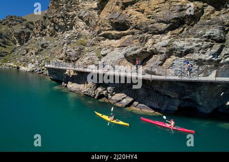 Cyclistes sur le pont en porte-à-faux sur la piste cyclable du lac Dunstan, et kayakistes, lac Dunstan, près de Cromwell, Central Otago, South Island, Nouvelle-Zélande - drone Banque D'Images