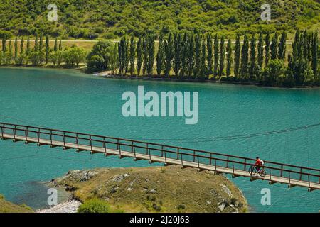 Pont suspendu Hugo sur le sentier du cycle du lac Dunstan et le lac Dunstan, près de Cromwell, Central Otago, South Island, Nouvelle-Zélande Banque D'Images