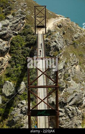 Pont suspendu Hugo sur le sentier du cycle du lac Dunstan et le lac Dunstan, près de Cromwell, Central Otago, South Island, Nouvelle-Zélande Banque D'Images