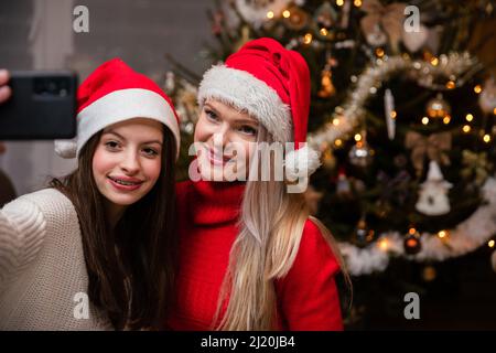 Maman et fille prennent un selfie après avoir décoré l'arbre de Noël. Banque D'Images