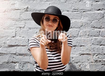 Vous avez vraiment bien compris. Portrait de jeune femme gaie pointant vers l'appareil photo avec les deux mains contre un mur de briques à l'extérieur. Banque D'Images