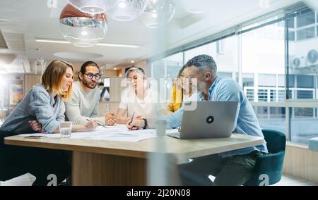 Divers concepteurs remue-méninges lors d'une réunion dans un bureau moderne. Équipe d'hommes d'affaires novateurs ayant une discussion tout en travaillant sur un nouveau crea Banque D'Images
