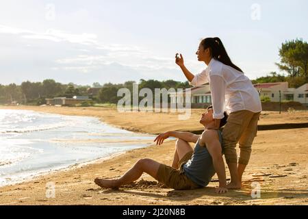 Un jeune couple prend des photos sur une plage d'été - photo de stock Banque D'Images