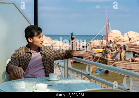 Jeune homme prenant des photos sur la plage - photo de stock Banque D'Images