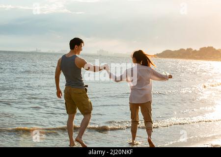 Jeune couple remplissant le message dans la bouteille de dérive sur la plage d'été - photo de stock Banque D'Images