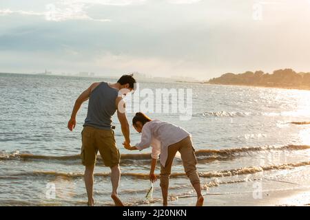 Jeune couple en train de découvrir une bouteille dérivant sur la plage d'été - photo de stock Banque D'Images