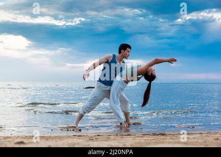 Jeune couple s'étendant sous les magnifiques nuages de bord de mer - photo de stock Banque D'Images