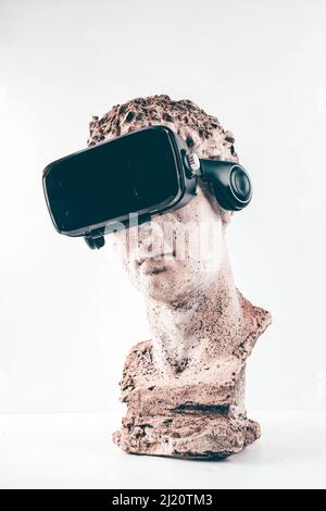 Statue ancienne avec lunettes VR sur fond blanc. Concept d'art et réalité virtuelle. Banque D'Images