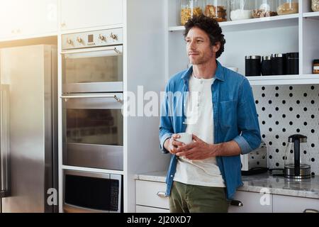 Café assez bon pour se perdre. Cliché d'un baccalauréat perdu dans la contemplation tout en buvant une tasse de café dans sa cuisine. Banque D'Images