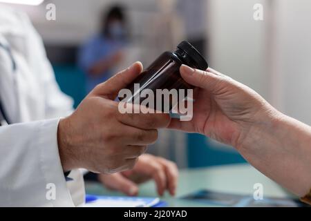 Mains du médecin et de la femme âgée tenant une bouteille de pilules au bureau. Spécialiste donnant une fiole de médicament à un adulte à la retraite après consultation médicale au rendez-vous de contrôle. Gros plan Banque D'Images