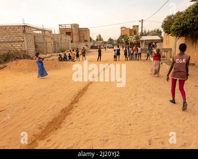 MBOUR, SÉNÉGAL, AFRIQUE - DÉCEMBRE CIRCA, 2021. De jeunes enfants africains non identifiés faisant une course de sacs dans la rue. Ils doivent remplir le bassin avec W Banque D'Images