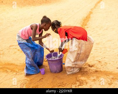 MBOUR, SÉNÉGAL, AFRIQUE - DÉCEMBRE CIRCA, 2021. De jeunes enfants africains non identifiés faisant une course de sacs dans la rue. Ils doivent remplir le bassin avec W Banque D'Images