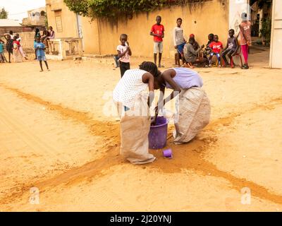 MBOUR, SÉNÉGAL, AFRIQUE - DÉCEMBRE CIRCA, 2021. De jeunes enfants africains non identifiés faisant une course de sacs dans la rue. Ils doivent remplir le bassin avec W Banque D'Images