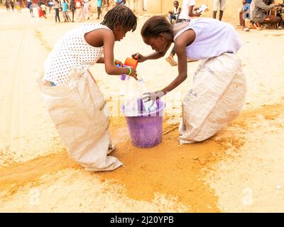 MBOUR, SÉNÉGAL, AFRIQUE - DÉCEMBRE CIRCA, 2021. De jeunes enfants africains non identifiés faisant une course de sacs dans la rue. Ils doivent remplir le bassin avec W Banque D'Images