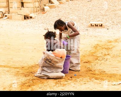 MBOUR, SÉNÉGAL, AFRIQUE - DÉCEMBRE CIRCA, 2021. De jeunes enfants africains non identifiés faisant une course de sacs dans la rue. Ils doivent remplir le bassin avec W Banque D'Images