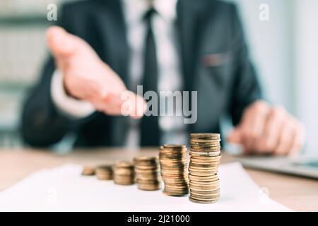 Banquier offrant le prêt financier, la fermeture de la personne d'affaires de col blanc dans le bureau avec des pièces empilées sur le bureau, foyer sélectif Banque D'Images