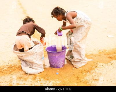 MBOUR, SÉNÉGAL, AFRIQUE - DÉCEMBRE CIRCA, 2021. De jeunes enfants africains non identifiés faisant une course de sacs dans la rue. Ils doivent remplir le bassin avec W Banque D'Images