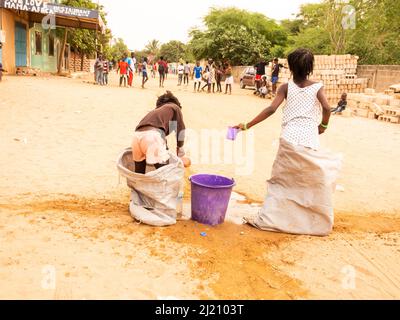 MBOUR, SÉNÉGAL, AFRIQUE - DÉCEMBRE CIRCA, 2021. De jeunes enfants africains non identifiés faisant une course de sacs dans la rue. Ils doivent remplir le bassin avec W Banque D'Images