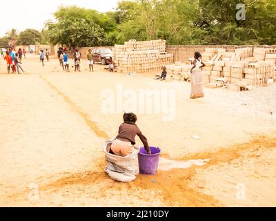 MBOUR, SÉNÉGAL, AFRIQUE - DÉCEMBRE CIRCA, 2021. De jeunes enfants africains non identifiés faisant une course de sacs dans la rue. Ils doivent remplir le bassin avec W Banque D'Images