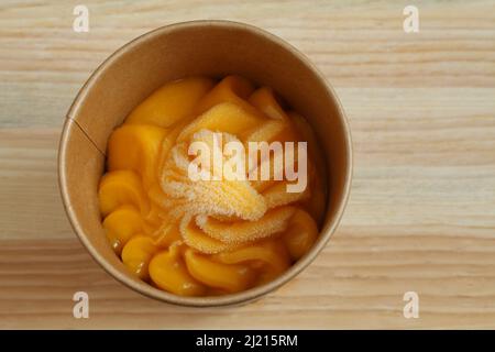 Sorbet mangue dans une tasse en carton se tient sur une table en bois. Gros plan. Vue de dessus Banque D'Images
