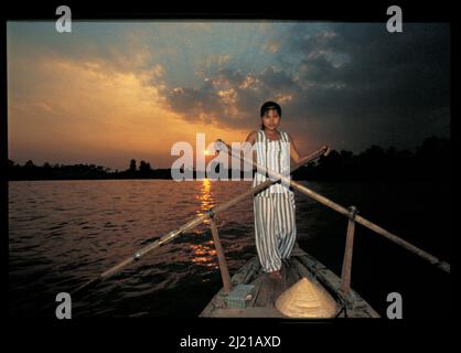 Une jeune femme vietnamienne se pagaie à travers le delta du Mékong au coucher du soleil près de CAN Tho, dans le sud du Vietnam. © Kraig Lieb Banque D'Images