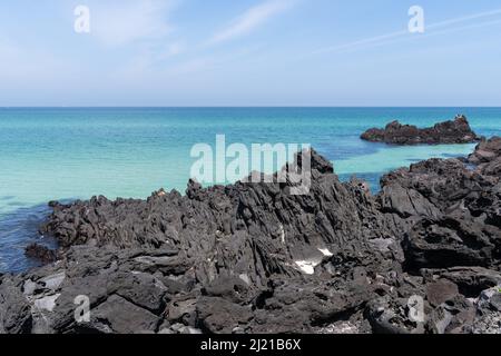 Des roches volcaniques noires jagrées jégarées de l'eau bleu marine cristalline le long de la plage de Hamam sur l'île de Jeju, en Corée du Sud Banque D'Images