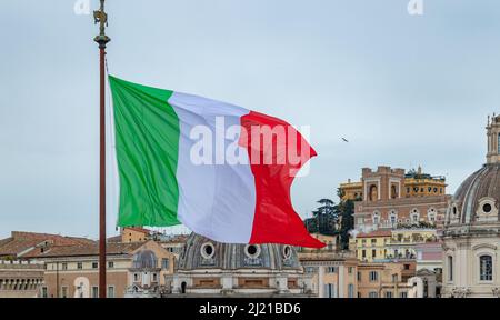 Une photo d'un grand drapeau italien qui s'agite à côté de certains monuments. Banque D'Images