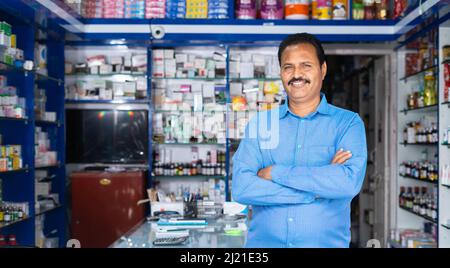 Portrait de heureux propriétaire de magasin médical debout avec les bras croisés en regardant la caméra à la pharmacie - concept de succès, petite entreprise et Banque D'Images