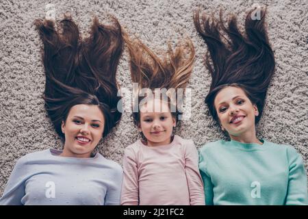 Haut au-dessus de la vue grand angle portrait de famille gaie attrayante copines se reposant en s'amusant couché sur la moquette à la maison à l'intérieur Banque D'Images