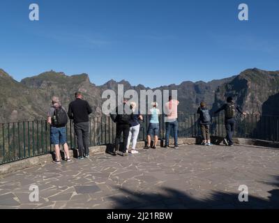 Touristes sur la plate-forme d'observation à Miradouro da Eira do Serrado regardant vers le village de la vallée des Nuns loin en dessous dans le cratère du volcan éteint Madeira Portug Banque D'Images