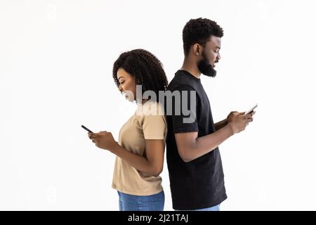 Un couple ethnique africain séduisant tient les smartphones s'amuser sur Internet Banque D'Images