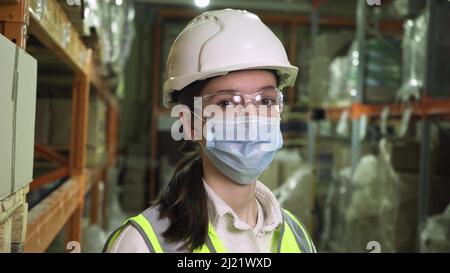 Portrait d'une travailleuse dans un gilet de protection, casque de sécurité, portant un masque médical Banque D'Images