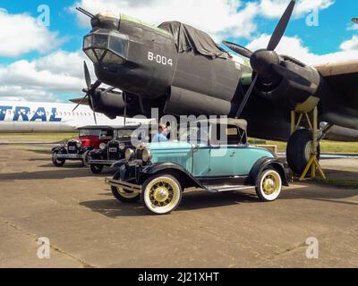 Ancien modèle de Ford cyan Un roadster coupé vers 1930 stationné devant un bombardier à quatre moteurs Avro Lincoln MKII de la Seconde Guerre mondiale 1944-1967. Salon de la voiture classique. CopySpace Banque D'Images